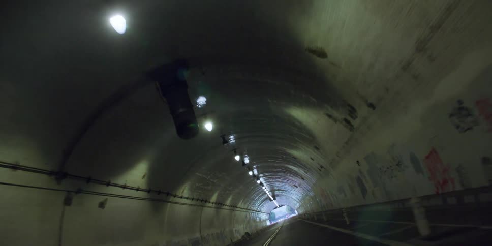 Lights line the top of the graffiti covered tunnel