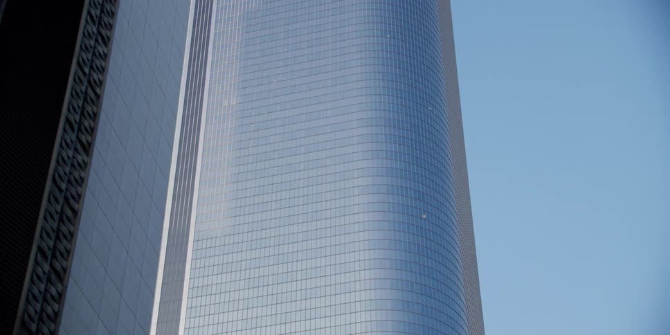 Glass covered tall building reflecting another skyscraper during day time