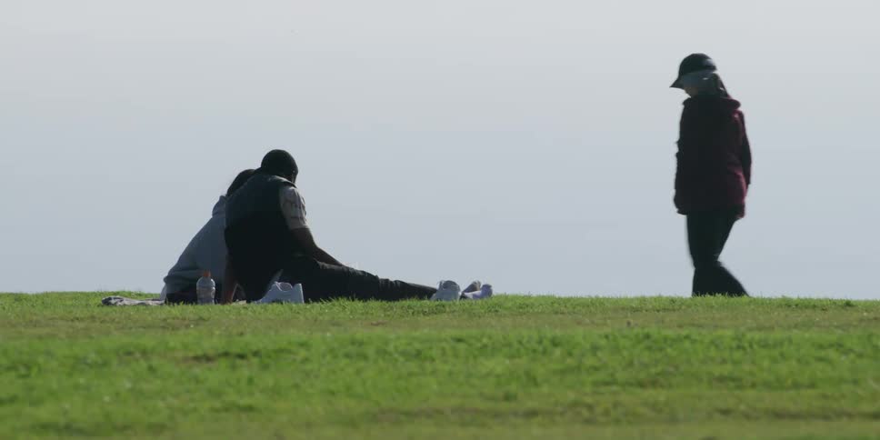 A couple enjoying a picnic on the lawn overlooking the coast on a windy day