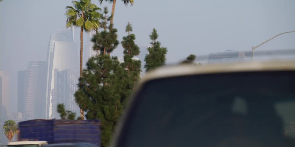 Cars driving in front of a city skyline during the day