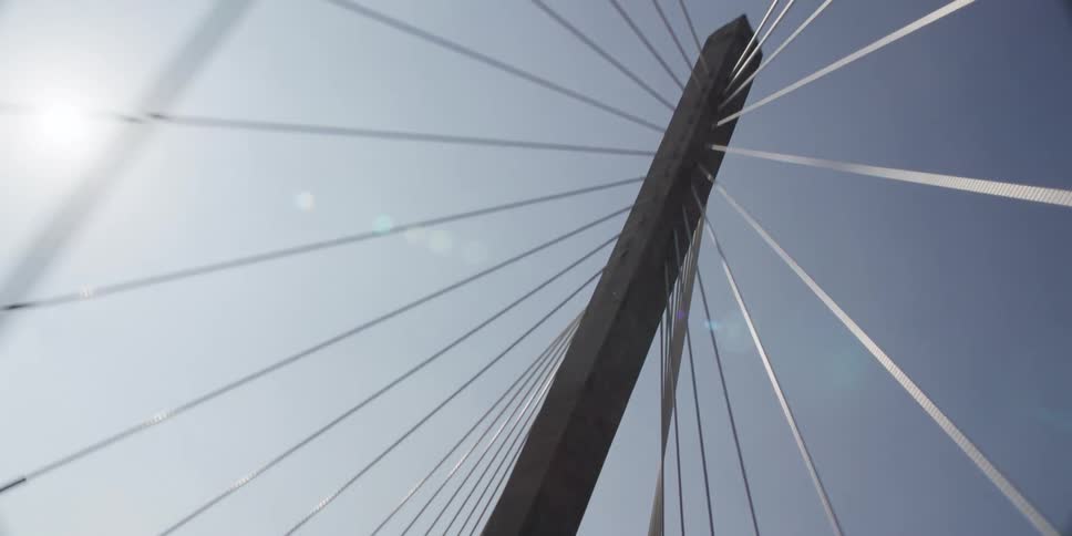 A skyward view of a suspension bridge while traveling during the daytime