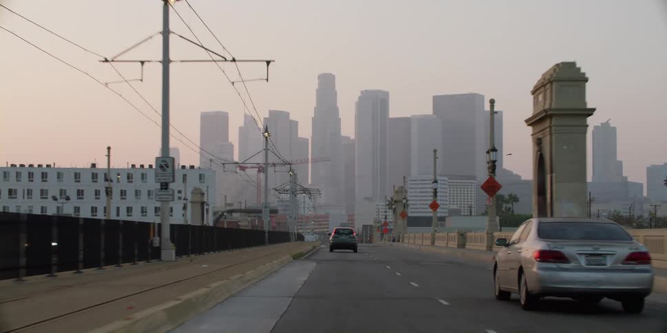 Vehicles drive down a bridge headed toward downtown