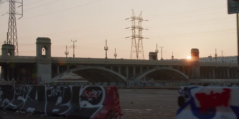 Barriers are marked with graffiti in an empty barren parking lot near energy stations