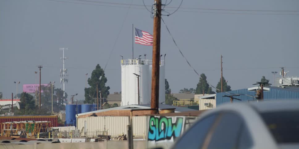 Passing by warehouses in an industrial urban area while in traffic on a breezy day