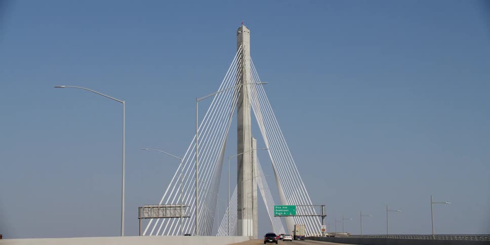 Vehicles drive down a long suspension bridge