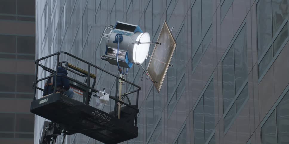 A man sits on the cherry picker with a spotlight