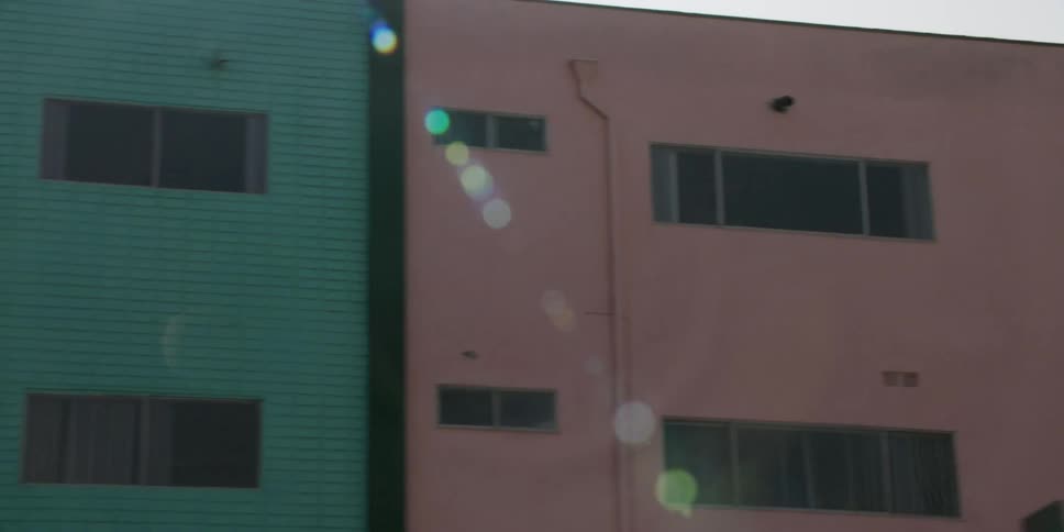 A green and pink residential building with multiple windows