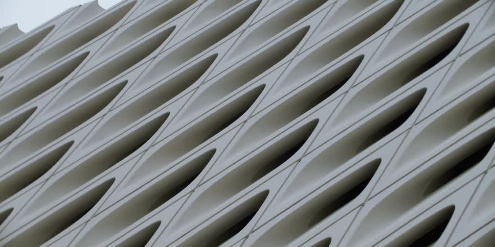 A passing view of an outdoor wall with a sculpted design pattern in the daytime