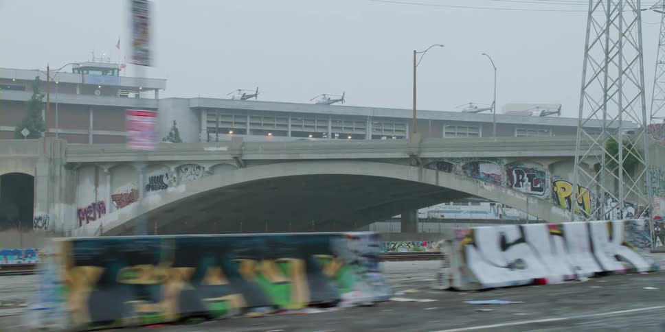 Cars travel on a highway overpass near the airport with helicopters on the roof deck