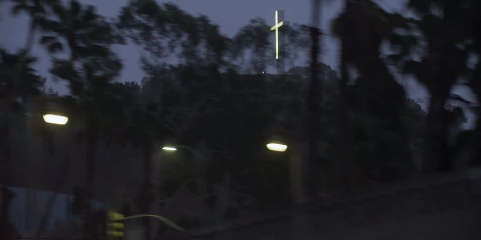 A glowing cross sits atop a steep hill