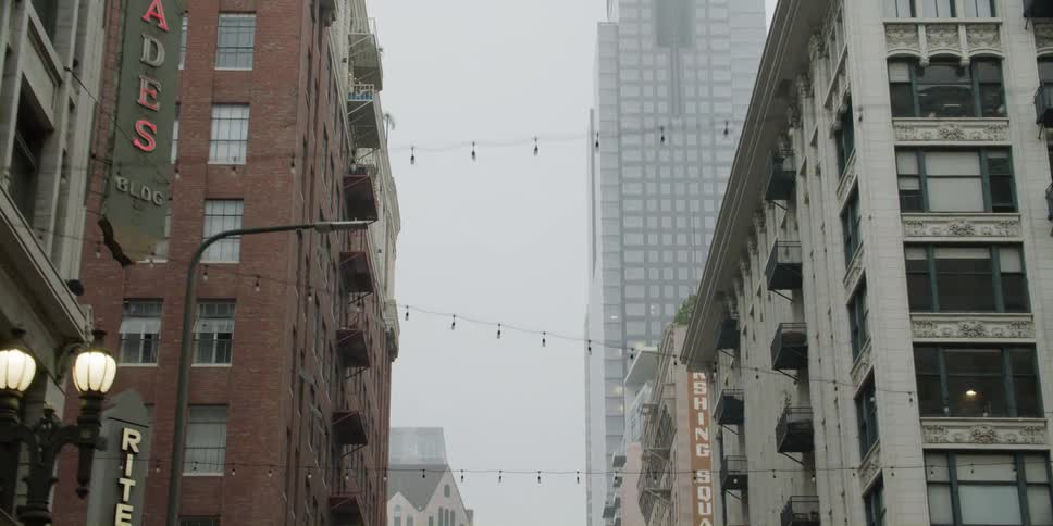 A tall city building towers into the foggy sky