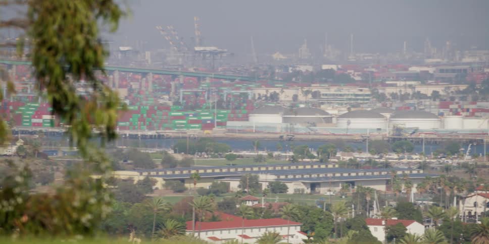 A neighborhood sits near a vast shipping port along the coast