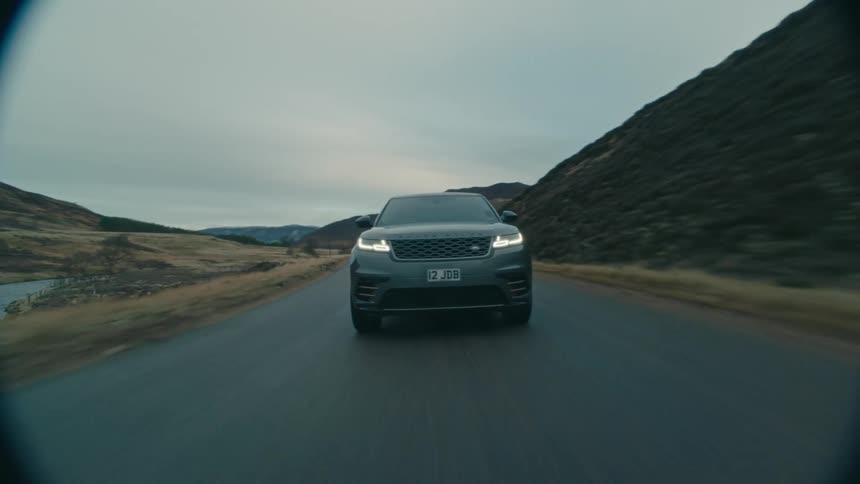 A car is driving down a road at dusk
