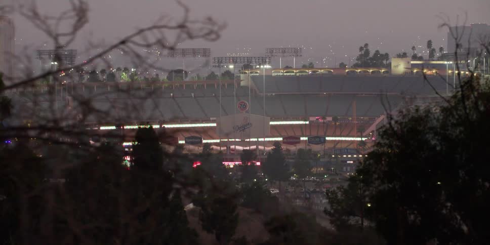 City lights shine through the fog covering stadium sitting near highway
