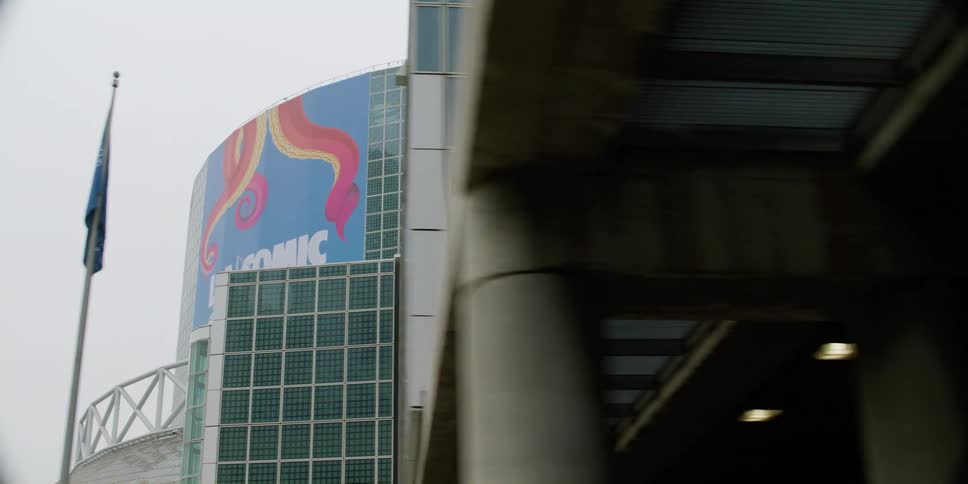A large banner outside a convention center advertises for a comic convention