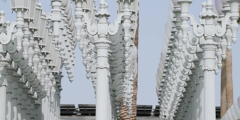Dozens of lamp posts sit in even narrow columns in front of a building