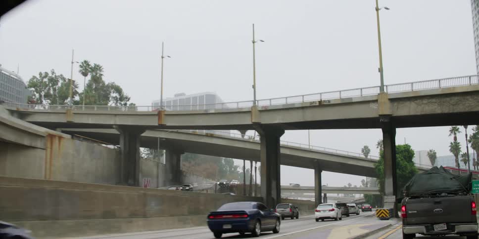 Vehicles travel on a highway and over a bridge in a city