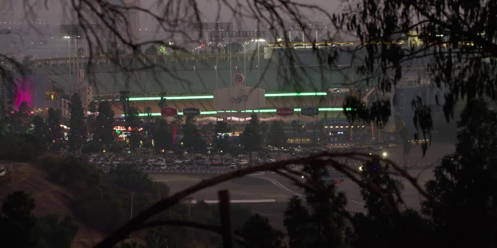 Vehicle passes briefly obscuring view of fog covered stadium and parking lot at night