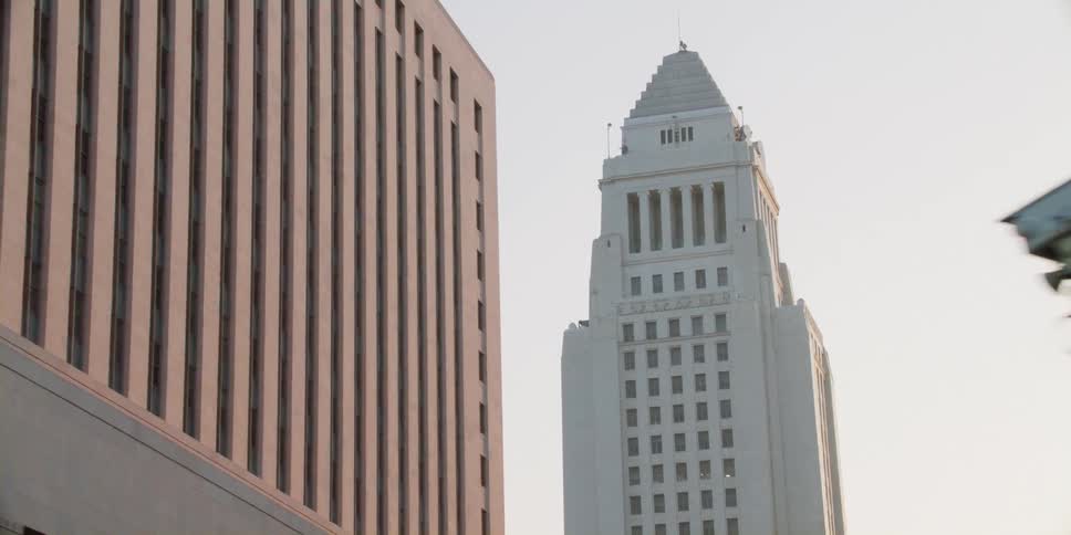 Tall city buildings with spire seen from moving vehicle in street