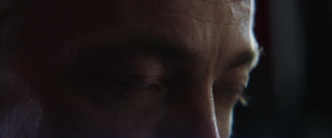 Middle aged and blue eyed man with gray ponytail works out in gym