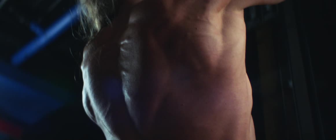The muscles on a mans back as he lifts weights