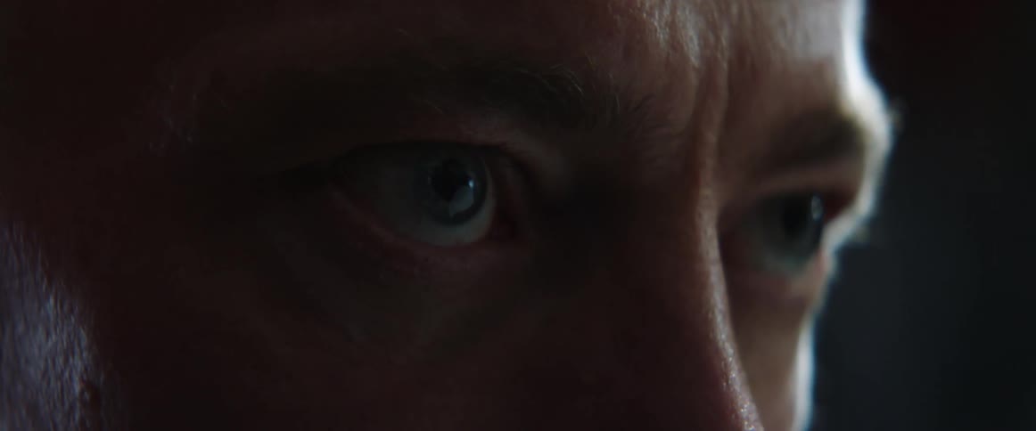 A man leans forward in the dark room