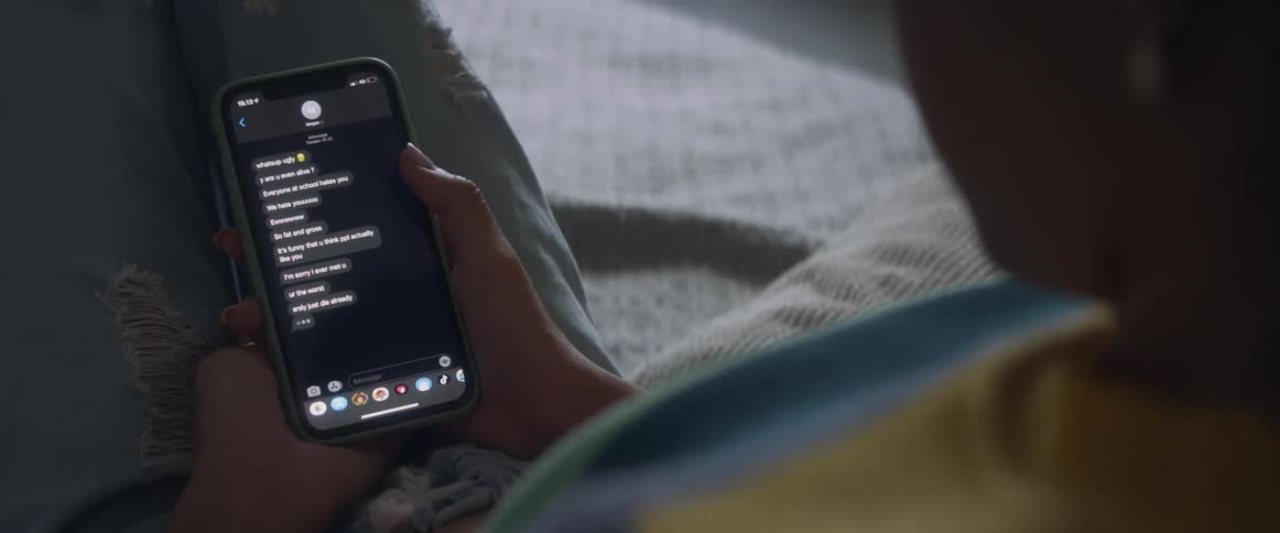 Woman looks at text on her cell phone then lays the phone down next to her