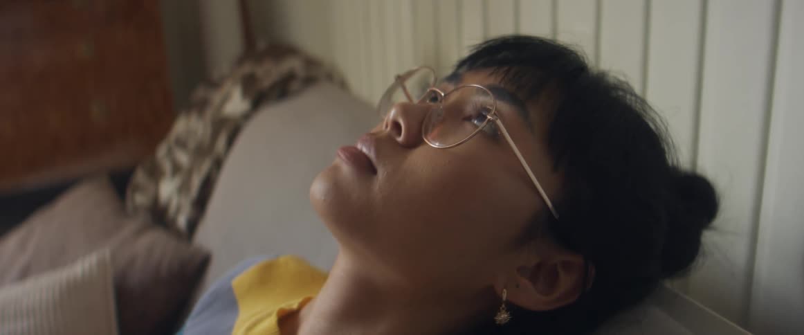 Woman sits with head leaning back frowning as she stares toward the ceiling