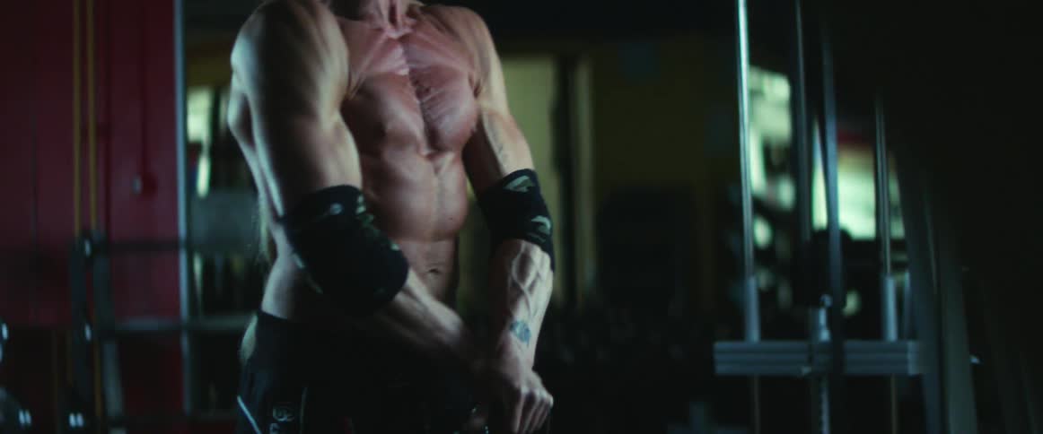 Middle aged and blue eyed man with gray ponytail works out in gym