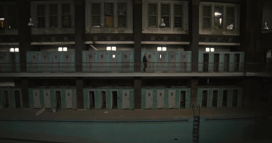 A prison guard walks past cell doors