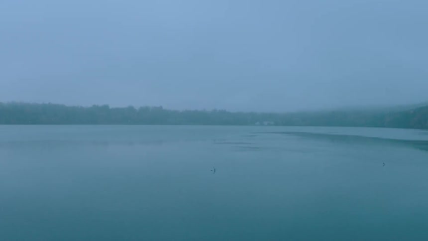 A large body of water is still on a foggy day