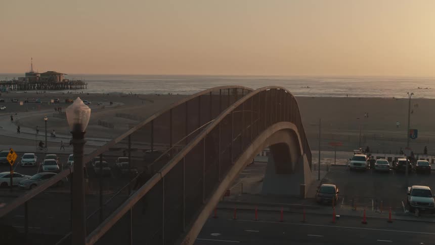An overpass as people travel around the beach at sunrise