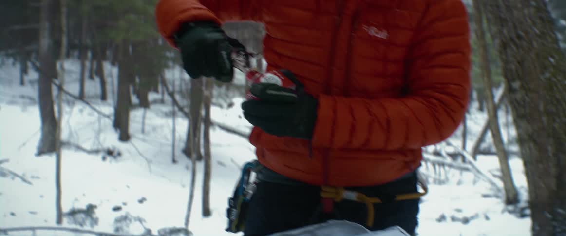A man sets up tools while camping in the woods