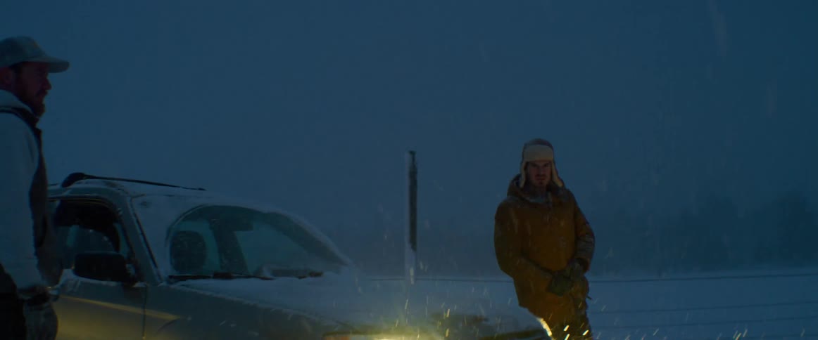 Two men shake hands in a snow storm