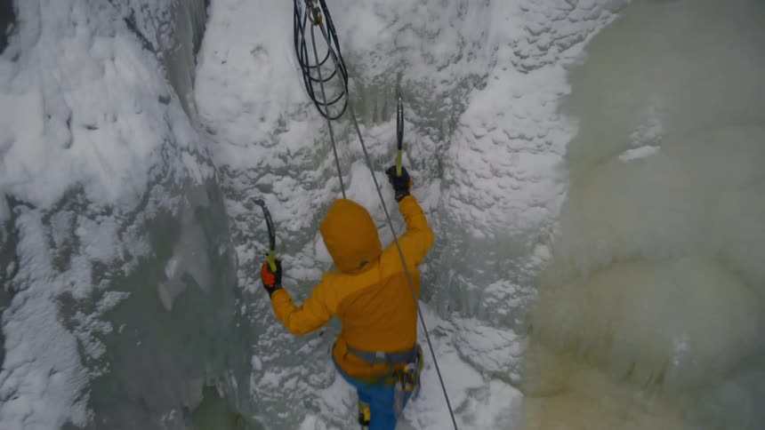 A person is rock climbing up a mountain in winter