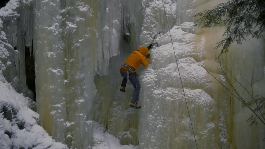 A man is climbing up the ice on the cliff