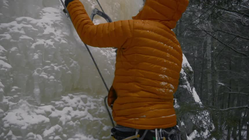 A person puts ice picks in the side of a mountain as they climb up