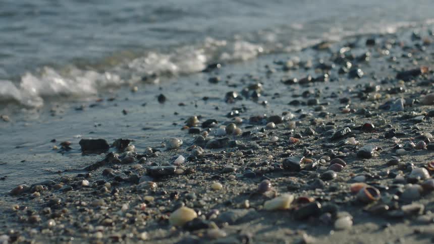 Waves roll in over stones and pebbles on a beach