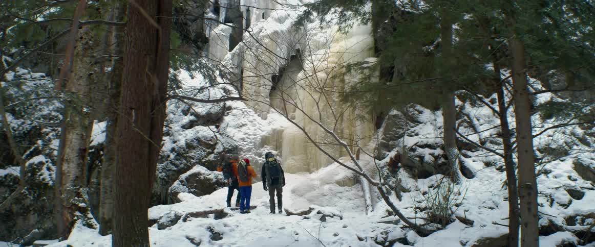 Backpackers stop in the woods to admire a frozen waterfall