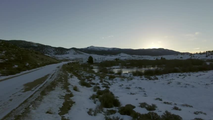 A snowy field leading toward a lake