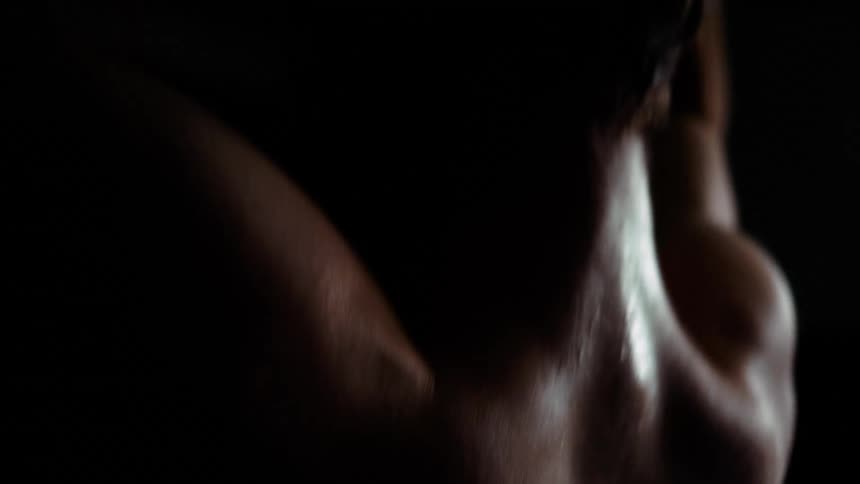 Shirtless white man doing pull ups in a dark room