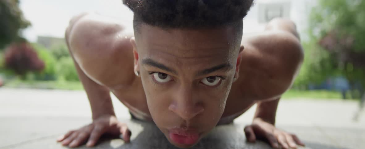 A young man does push ups on an open tarmac area