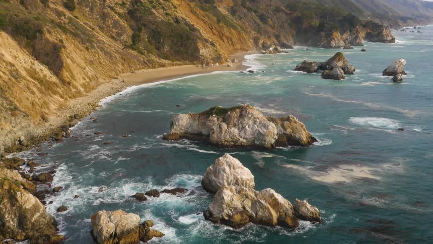 Aerial view of ocean waves crashing against the cliffside