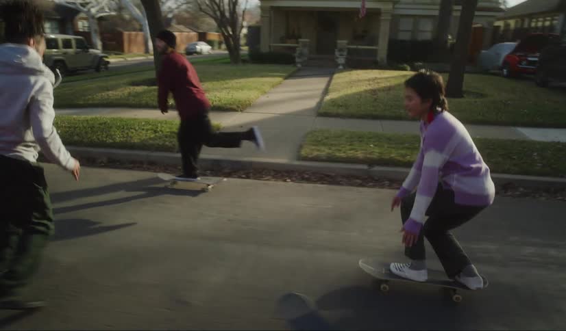 Three teenagers ride their skateboard down the street