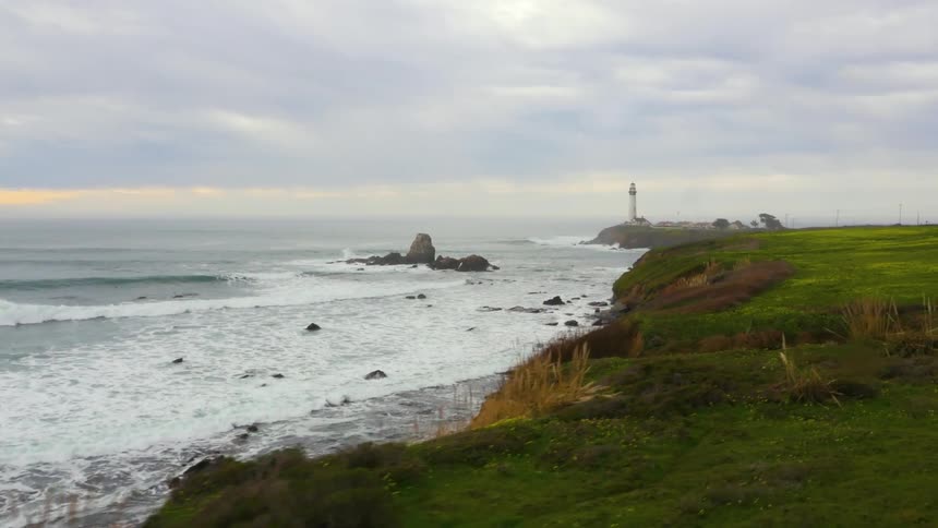 Waves crash along the coast near a lighthouse