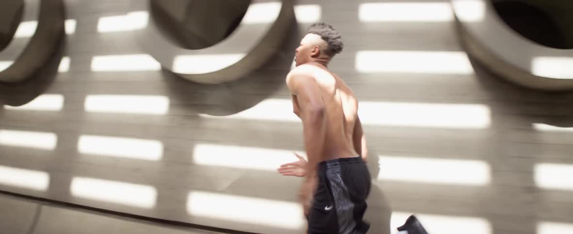 Black man wearing a black short and shoes running alone at an indoors structure