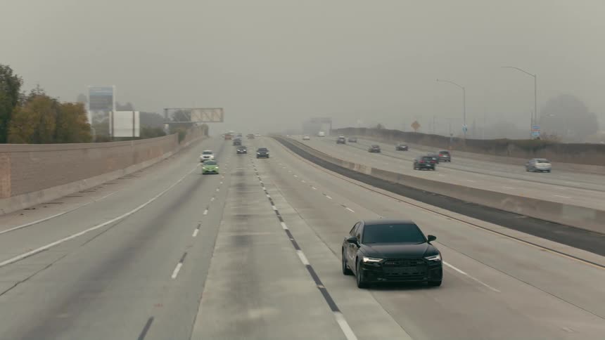 A black vehicle changes lanes on the highway