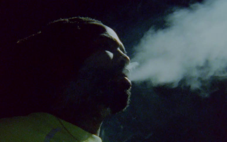 A black man is smoking in the darkness