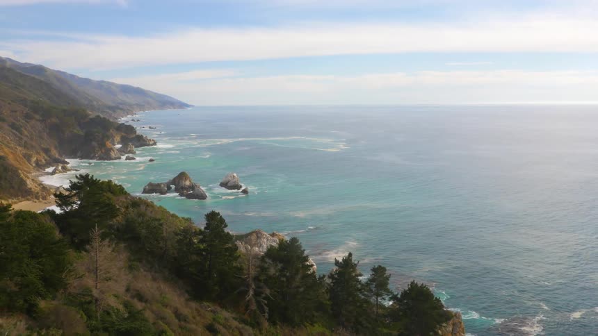 Aerial view of the coastline as waves splash against the rocks and roll in over the beach
