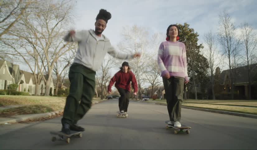 Three people skateboard down the street